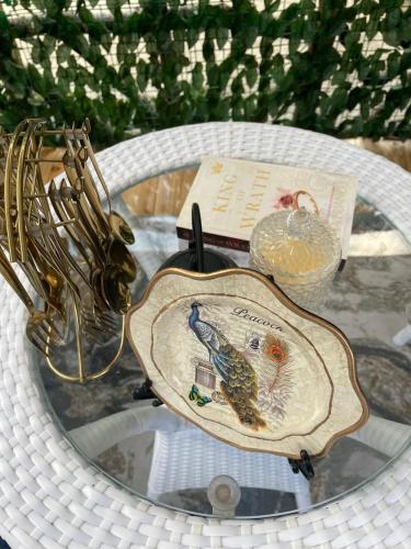 a glass table with a plate with a bird on it at Lee's Grandma's Will Cottage in Kalimpong