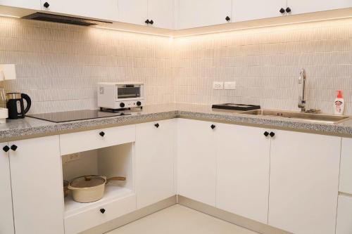 een keuken met witte kasten en een magnetron bij KNV Apartment in Thu Dau Mot