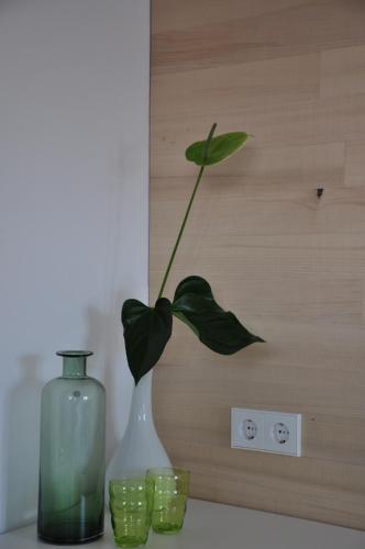 a green vase with a plant in it next to two green glasses at DIE KRONE - Hotel Garni in Kirchzarten