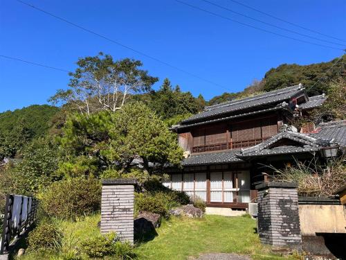 an asian house with a mountain in the background at ゲストハウスサンテ in Susaki