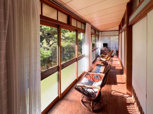 a screened porch with two benches and windows at ゲストハウスサンテ in Susaki