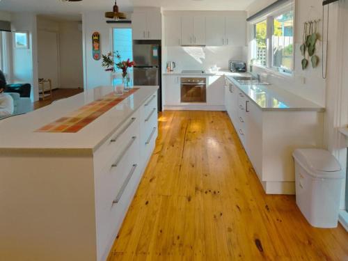 cocina con armarios blancos y suelo de madera en Sitara Cottage, en Yanakie