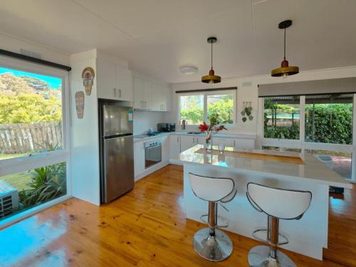 Una cocina con gabinetes blancos y electrodomésticos de acero inoxidable. en Sitara Cottage, en Yanakie