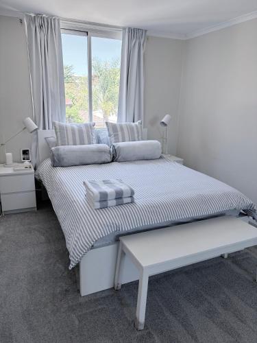 a white bedroom with a large bed with a window at Coastal Comfort In The Heart Of Coogee in Sydney