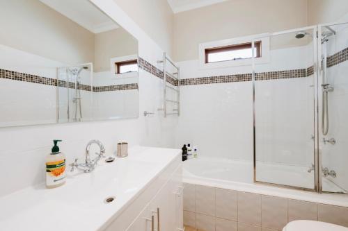 a white bathroom with a tub and a shower at A Market Place Mudgee - Walk to Town Centre & Parks in Mudgee