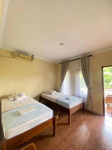a bedroom with two beds and a window at Opak Village Bed & Breakfast in Bantul