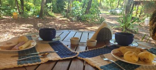 a table with two plates of bread and two cups at Bangalô Rústico Duplex - Retiro Andaluz in Brumadinho