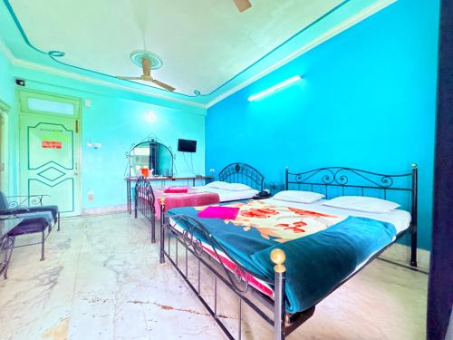 two beds in a room with blue walls at বীণাপানি হোটেল & রেস্টুরেন্ট Binapani Tarapith in Tarapith