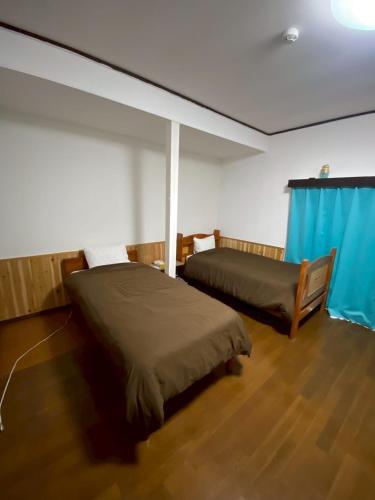 a bedroom with two beds and a blue curtain at Lagoon藍yoron 一棟貸し in Yoron