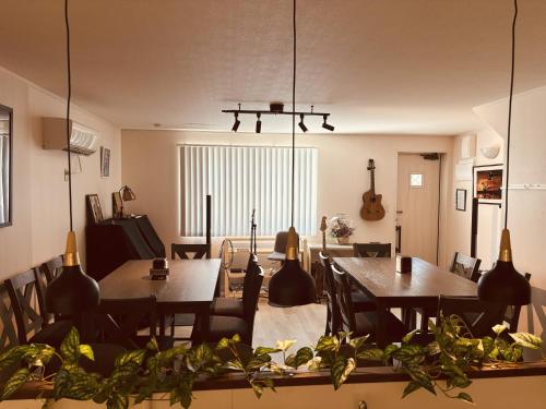 uma sala de jantar com mesas e cadeiras e uma guitarra em Jazz 喫茶 Eju イージュ B&B em Urazoe