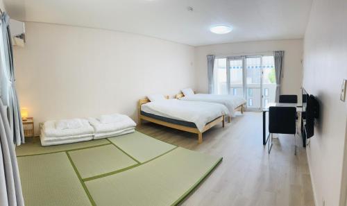 a white room with two beds and a television at 浦添民泊ejuイージュ in Urazoe