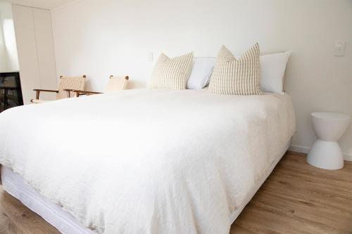 a bedroom with a white bed with white sheets and pillows at The Coconut Hut Papamoa Beach in Tauranga