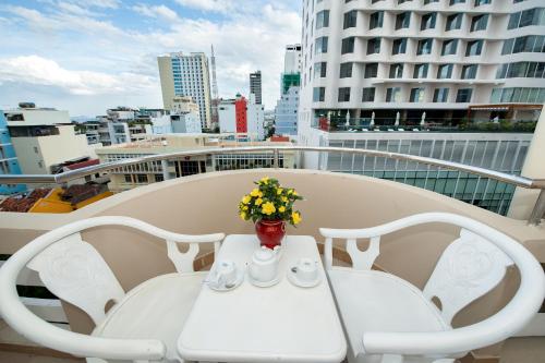 a white table with a vase of flowers on a balcony at Palm Beach Hotel in Nha Trang