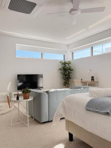 a living room with a couch and a tv at Casa Lumi Walk to Marina & Beach in Shellharbour
