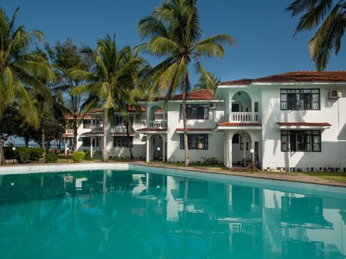 a house with a swimming pool in front of it at Bahari Dhow Beach Villas in Diani Beach