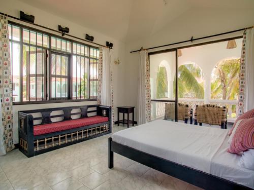 a bedroom with a bed and large windows at Bahari Dhow Beach Villas in Diani Beach