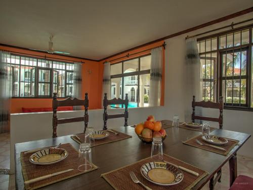 a dining room with a table and chairs and windows at Bahari Dhow Beach Villas in Diani Beach