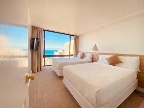 a hotel room with two beds and a large window at Newly renovated luxury, modern style Waikiki Sunset Hotel Ocean view Freeparking in Honolulu
