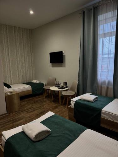 ein Hotelzimmer mit drei Betten und einem Flachbildfernseher in der Unterkunft Hotel DoZari in Korostyshiv