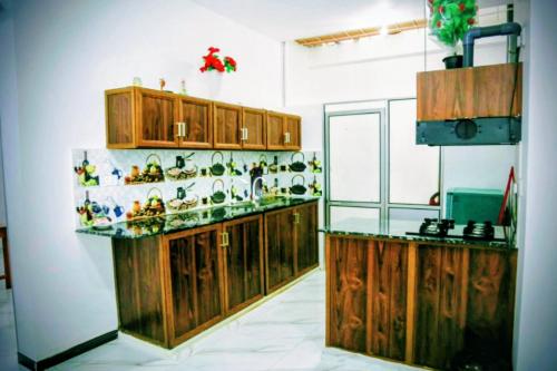 une cuisine avec des armoires en bois et un comptoir dans l'établissement Jaffna Guest House, à Jaffna