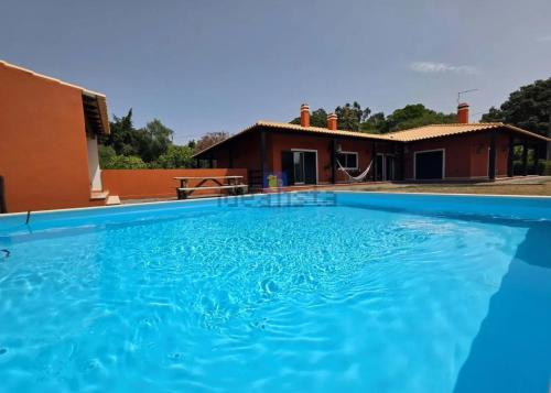 a large blue swimming pool in front of a house at A casa das minhas netas in Caldas da Rainha