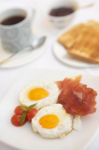two eggs and bacon on a plate with a cup of coffee at Jet Hotel in Caselle Torinese