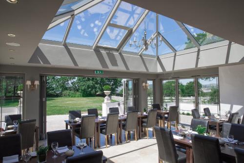 a conservatory with tables and chairs and windows at Llechwen Hall in Pontypridd