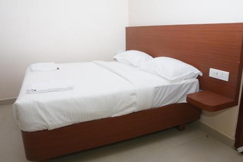 a bed with white sheets and a wooden head board at sri selvaas inn in Kanchipuram