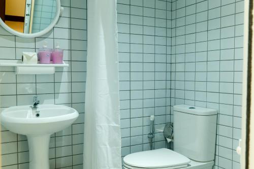 a white tiled bathroom with a toilet and a sink at The Golden Beach Resort Naiyang in Nai Yang Beach