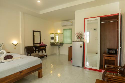 a bedroom with a bed and a refrigerator in it at The Golden Beach Resort Naiyang in Nai Yang Beach