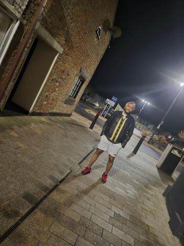Ein Mann steht nachts auf einem Bürgersteig in der Unterkunft Mulberry Suites in Cleethorpes