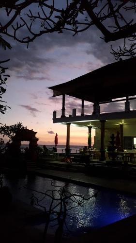 a building with a sunset in the background at Puri Oka Beach Bungalows in Candidasa