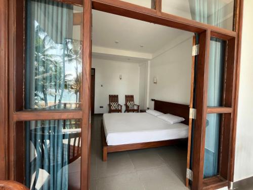 a bedroom with a bed and a glass door at Kiyoko Villa in Maha Induruwa