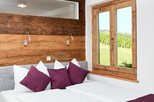 1 cama con almohadas moradas y blancas en una habitación con ventana en Weinberg Lodge - Kellerstöckl, en Klöch