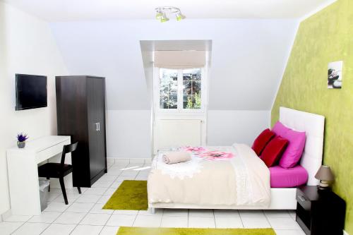 um quarto com uma cama com almofadas cor-de-rosa e uma secretária em L'Eden Orly Aéroport em Thiais