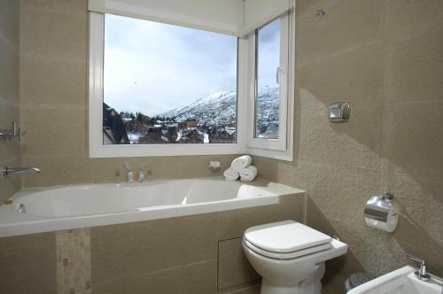 サン・カルロス・デ・バリローチェにあるVillage Condoのバスルーム(バスタブ、トイレ付)、窓が備わります。