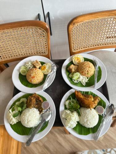 vier Teller mit Essen auf einem Tisch mit Reis in der Unterkunft HANAYA Living House Pacitan in Pacitan
