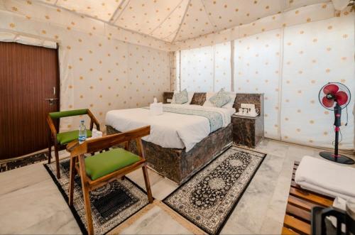 a bedroom with a bed and a chair in a room at Jaisalmer Desert Camp in Sām