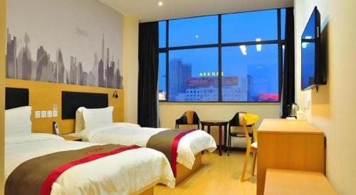 a hotel room with two beds and a large window at Thank Hotel Jiangxi Jiujiang Lianxi District Railway Station Square in Jiujiang
