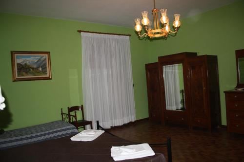 een slaapkamer met groene muren en een bed en een kroonluchter bij Agriturismo Casale 1921 in Torre le Nocelle