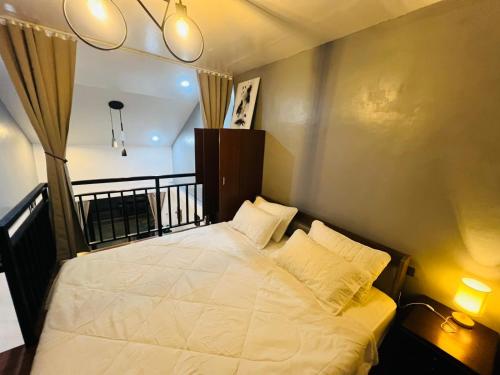 a bedroom with a white bed with two pillows at Homey Hideout- Athena and Noah Units in Magalang