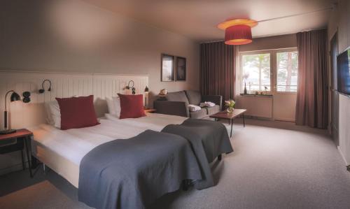 ein Schlafzimmer mit einem großen weißen Bett mit roten Kissen in der Unterkunft Almåsa Havshotell in Västerhaninge