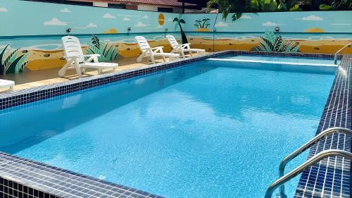 a large swimming pool with two chairs at Royal Agate Beach Resort in Pantai Cenang