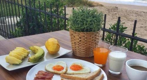 une table avec une assiette d'œufs, de pain et de fruits dans l'établissement Joy Hotel, à Khao Khan Kradaj