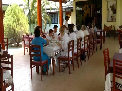 eine Gruppe von Menschen, die an einem Tisch in einem Restaurant sitzen in der Unterkunft Saji-Sami Hotel in Anuradhapura