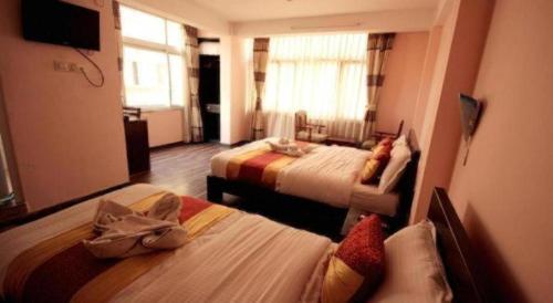 ein Hotelzimmer mit zwei Betten und einem Fernseher in der Unterkunft De Hotel Veda in Kathmandu