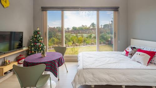 a bedroom with a christmas tree and a large window at Jeju moridarakbang pension in Jeju