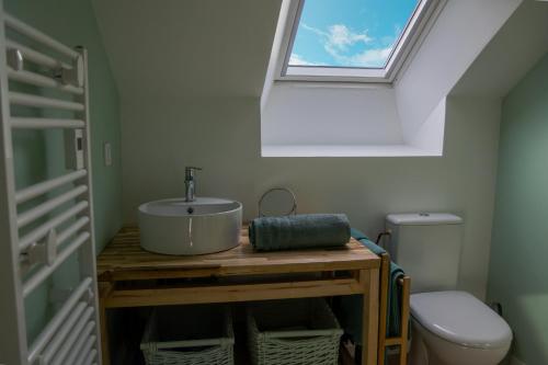 een badkamer met een wastafel en een toilet met een dakraam bij Bel appartement centre de Cancale in Cancale