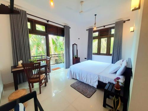 a bedroom with a bed and a desk and windows at Turtle Point Homestay Seaview 2 - BB, Fast Wi-Fi, AC in Dickwella