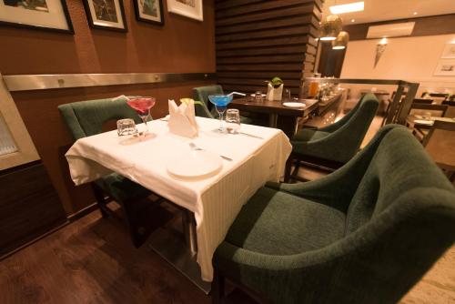 a table in a restaurant with green chairs and a table with a white table cloth at Hotel Le Grande - Mumbai International Airport in Mumbai
